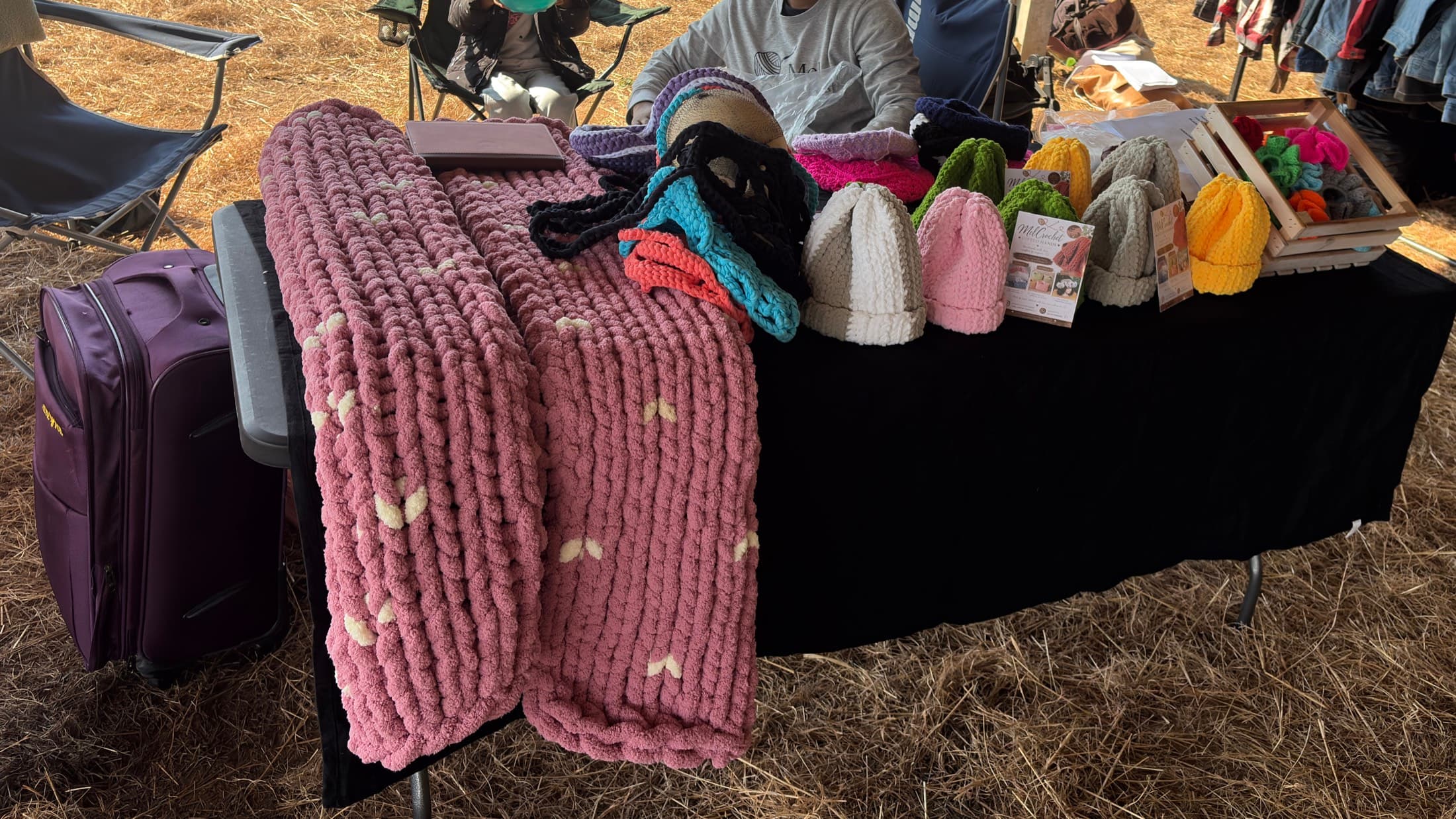 MelCrochet handmade blankets, hats, and scrunchies displayed at a market stall